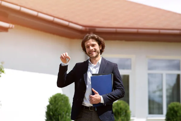 Joyful property manager with documents holding key to new house outdoors — Stock Photo, Image