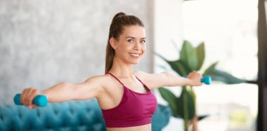 Milenyum bayanı evde dambıllarla egzersiz yapıyor.