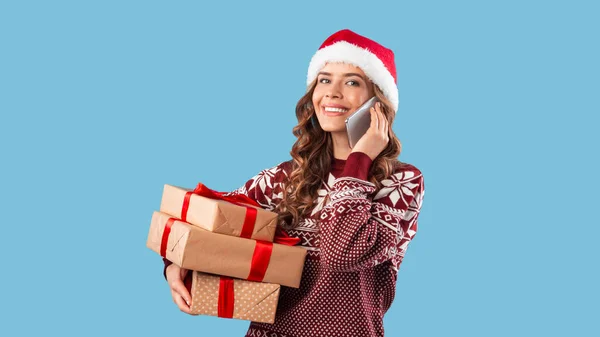 Sexy dama con regalos de Navidad hablando en el teléfono celular sobre fondo azul — Foto de Stock