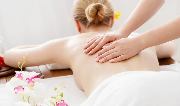 Relájese y spa. Las manos femeninas en la espalda desnuda chica en la mesa de masaje —  Fotos de Stock