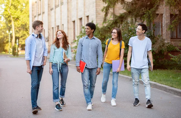 Багаторасові старшокласники ходять університетським кампусом на відкритому повітрі — стокове фото