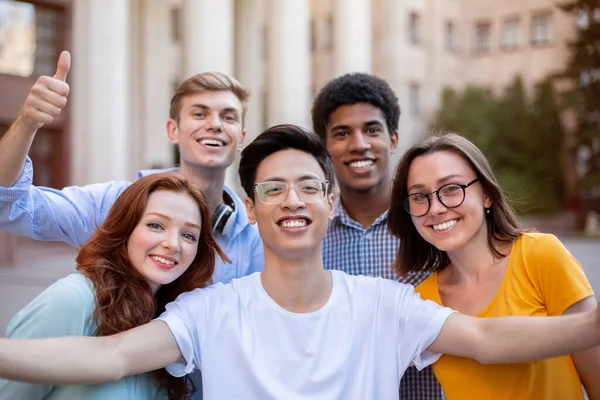 Alegres estudiantes multiculturales posando juntos haciendo selfie cerca del edificio de la universidad —  Fotos de Stock
