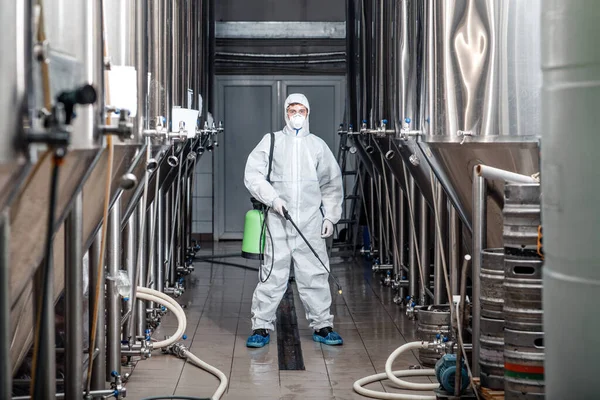 Hombre joven que trabaja en la fábrica de fabricación en traje de protección y limpia — Foto de Stock