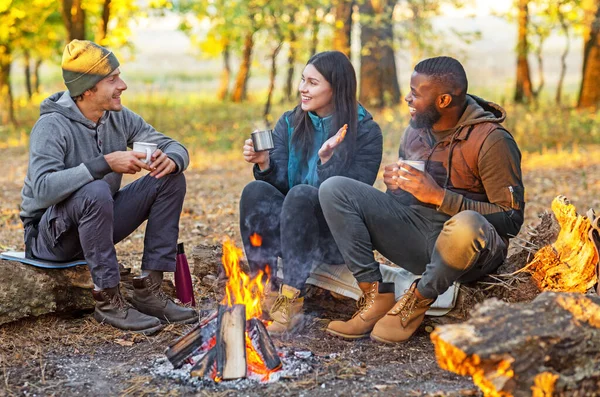 Group of closed friends enjoying hot tea at camp