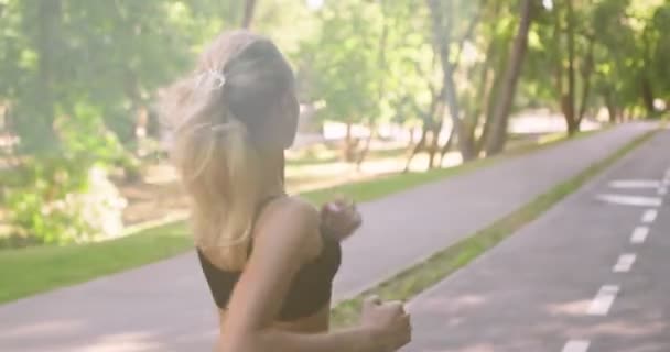 Actief blond meisje joggen op speciale trainingspad in openbaar park vroeg in de ochtend — Stockvideo