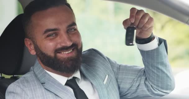 Magabiztos üzletember mosolyog a kamerába, és bemutatja az új autó kulcsát, közelről — Stock videók