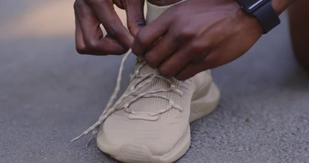 Nahaufnahme eines schwarzen Mannes, der Schnürsenkel an Turnschuhen bindet — Stockvideo