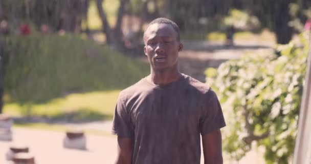 Esportista afro-americano cansado esfriando após o treino de corrida perto da fonte no parque urbano — Vídeo de Stock