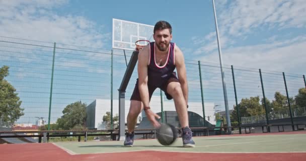 Ниже вид на парня тысячелетия дриблинг баскетбольный мяч к камере — стоковое видео