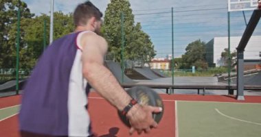 Aktif Kafkasyalı basketbolcu açık sahada potaya top atıyor.