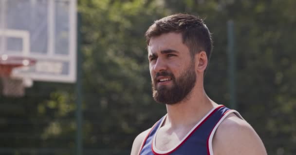 Close up de jovem desportivo cara beber água na quadra de basquete ao ar livre — Vídeo de Stock