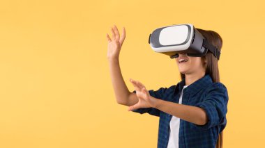 Turuncu stüdyoda sanal gerçeklik gözlüğü takan küçük bir kız.