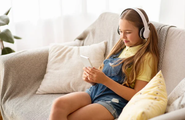 Flicka bär headset njuter av musik med telefon — Stockfoto