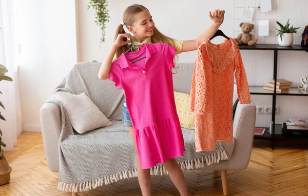 Blij jong meisje kiezen tussen twee jurken — Stockfoto