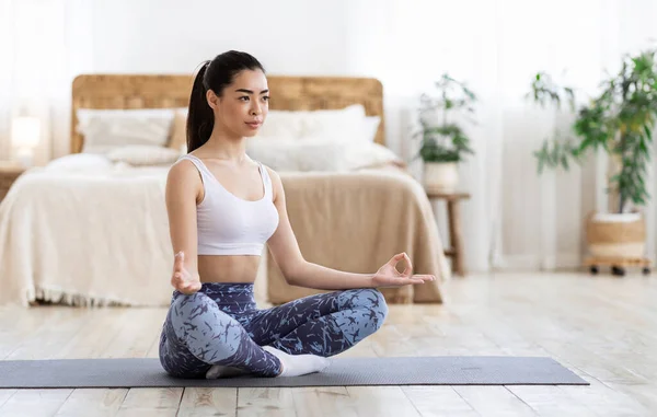 Balance de vida. Chica asiática practicando yoga en casa, meditando en posición de loto — Foto de Stock