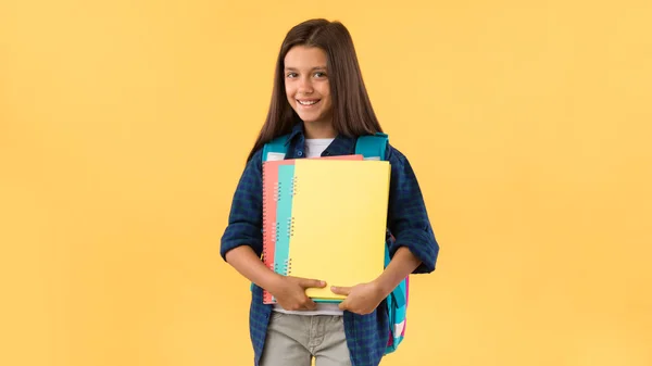 Glimlachend schoolmeisje met schoolboeken in de studio achtergrond — Stockfoto