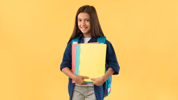 Usmívající se školačka drží učebnice na pozadí studia — Stock fotografie