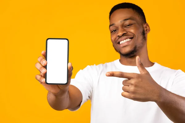 Hombre afroamericano mostrando pantalla de teléfono móvil, fondo amarillo, burla — Foto de Stock