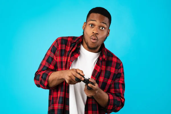 Black Millennial Guy Παίζοντας παιχνίδια βίντεο στέκεται πάνω από το μπλε φόντο — Φωτογραφία Αρχείου