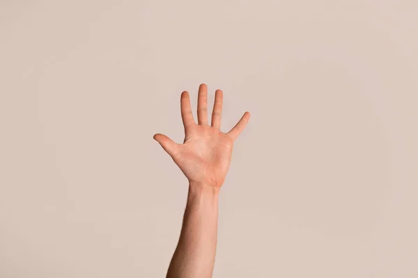 Giovane ragazzo che mostra la mano con il palmo aperto, gesticolando il cinque su sfondo chiaro, primo piano — Foto Stock