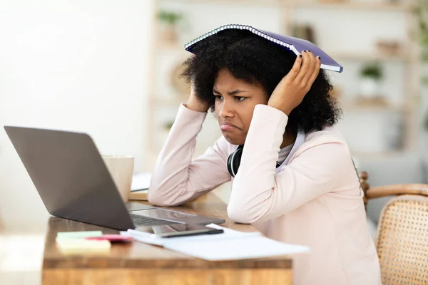 Triste negro chica en portátil cubierta cabeza con ejercicio-libro interior —  Fotos de Stock