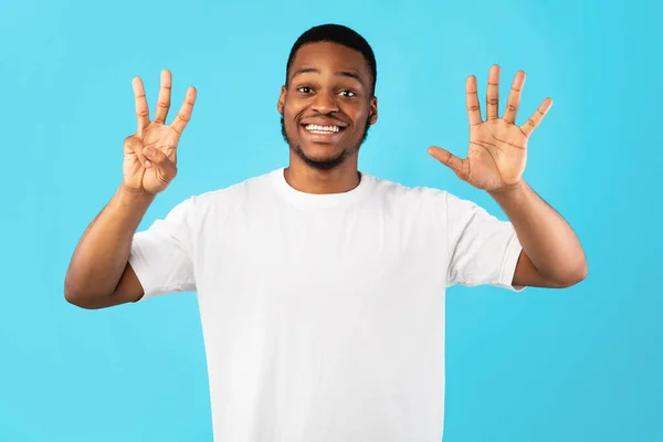 Hombre negro mostrando el número ocho contando con los dedos, fondo azul — Foto de Stock