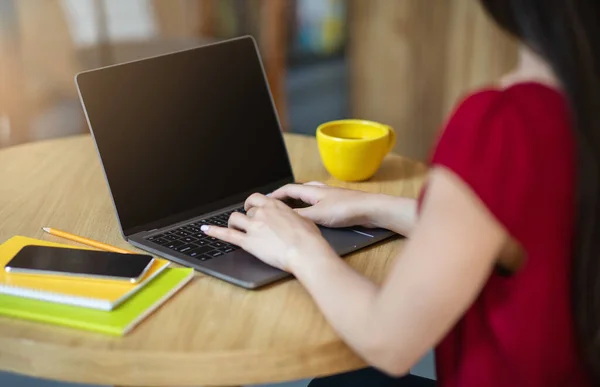 Mulher irreconhecível digitando no laptop com tela preta no café, imagem mockup — Fotografia de Stock