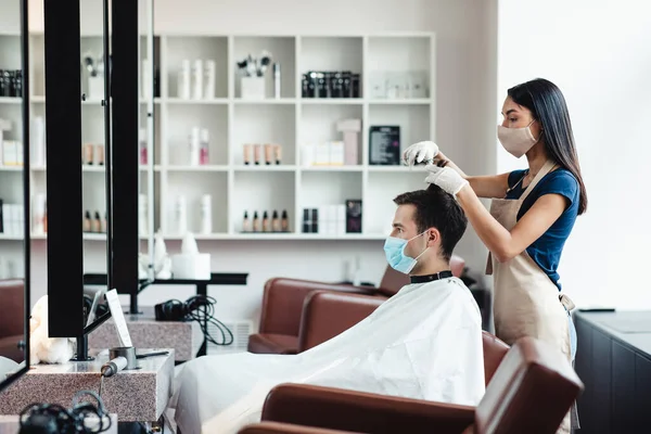 Cabeleireiro e cliente tomando precauções durante o corte de cabelo na barbearia — Fotografia de Stock