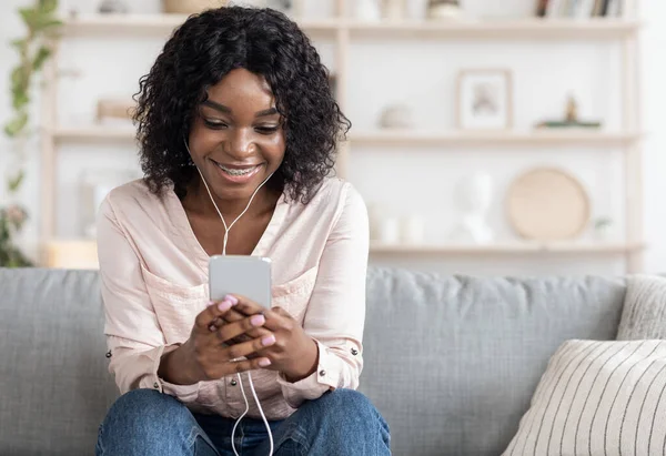 Passatempo doméstico. Relaxado Africano americano menina ouvir música com smartphone e fones de ouvido — Fotografia de Stock