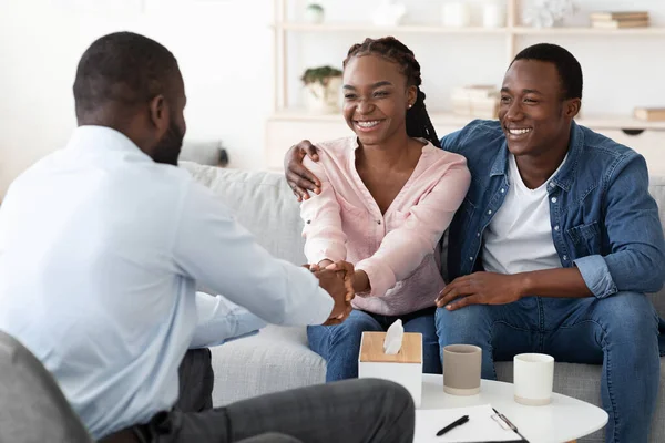Reconciliação matrimonial. Feliz casal negro grato ao conselheiro familiar após a terapia bem sucedida — Fotografia de Stock