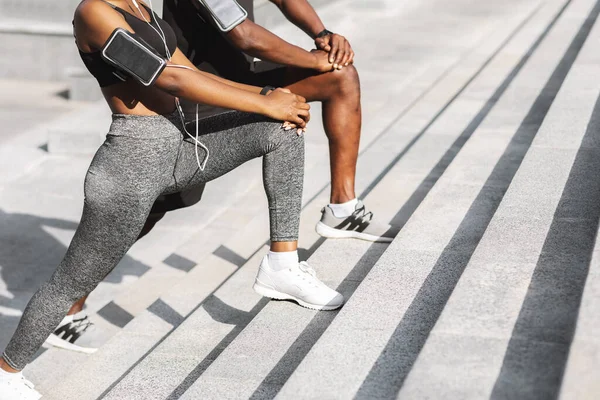 Tanımlanamayan siyah çift spor kıyafetleriyle dışarıda birlikte egzersiz yapıyor, bacak kaslarını esnetiyorlar. — Stok fotoğraf