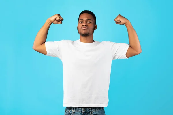 Stark svart kille visar biceps Posing på blå bakgrund — Stockfoto