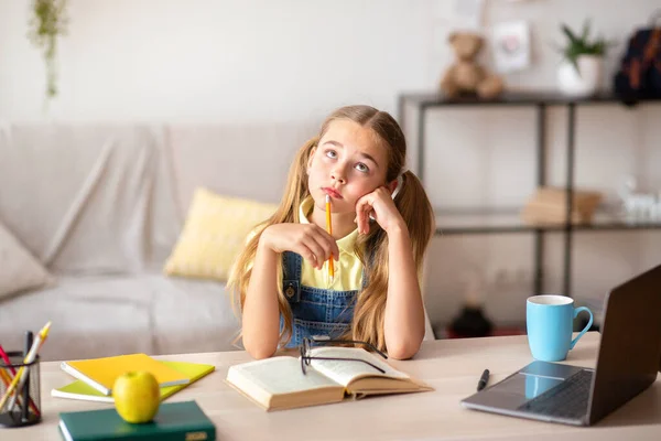 Chica pensativa sentada en el escritorio, haciendo tarea en casa — Foto de Stock