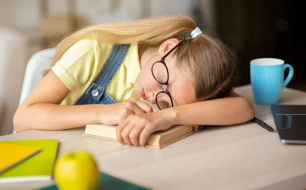 Cansada menina da escola dormindo à mesa com livro — Fotografia de Stock