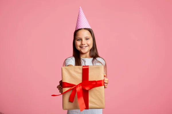 Doğum günü hediyesi. Kırmızı kurdeleli, hediye kutusu olan şapkalı mutlu küçük kız. — Stok fotoğraf