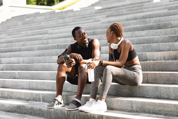 Θετικό αφρικανικό ζευγάρι που ξεκουράζεται μετά την άσκηση γυμναστικής Εξωτερικές πόρτες, κάθεται σε αστικές σκάλες — Φωτογραφία Αρχείου