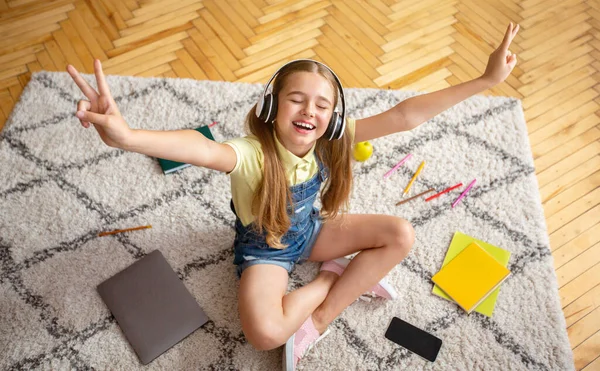 Girl listening to music sitting on the floor carpet — Stock Photo, Image