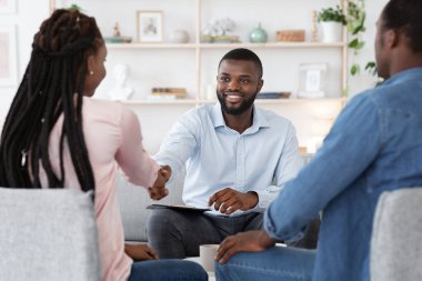 Başarılı terapiden sonra aile danışmanı mutlu siyah çiftle tokalaşıyor.