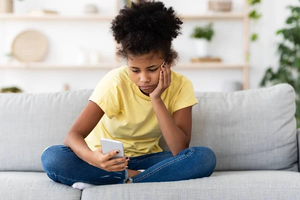 Verveeld Afrikaans amerikaans tiener meisje met behulp van smartphone zitten thuis — Stockfoto
