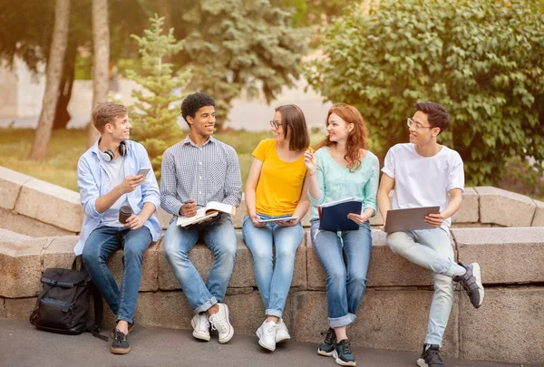 Estudiantes de secundaria aprendiendo haciendo tareas juntos sentados fuera —  Fotos de Stock