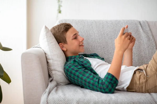 Вид сбоку счастливого подростка, играющего в игры на мобильном телефоне — стоковое фото