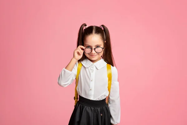 Primeiro dia de aulas. Menina alegre em uniforme tira óculos e olha para a câmera — Fotografia de Stock