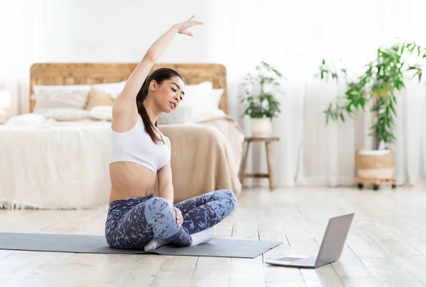 Home Sport. Ajuste asiático chica entrenamiento en frente de la computadora portátil, estiramiento de los músculos — Foto de Stock