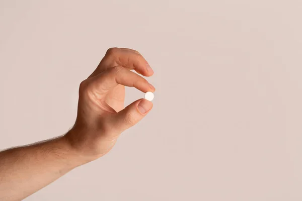 Chico joven irreconocible sosteniendo píldora sobre fondo claro, espacio en blanco — Foto de Stock
