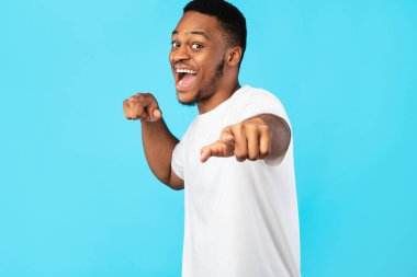Black Man Pointing Fingers At Camera Over Blue Studio Background clipart