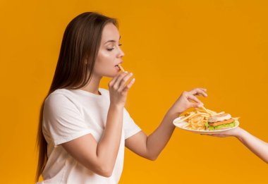 Fast Food ile tabaktan patates kızartması alan genç bir kız.