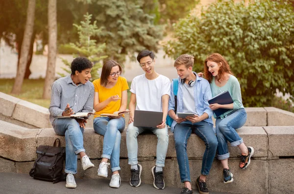 Estudiante chino mostrando sitio web educativo en el ordenador portátil a los compañeros de curso fuera — Foto de Stock