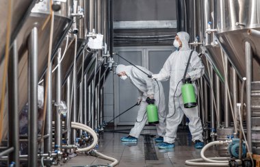 El yapımı bira fabrikası, ekolojik ürün ve dezenfeksiyon. Tehlikeli madde giysileri içindeki işçiler temiz fabrika