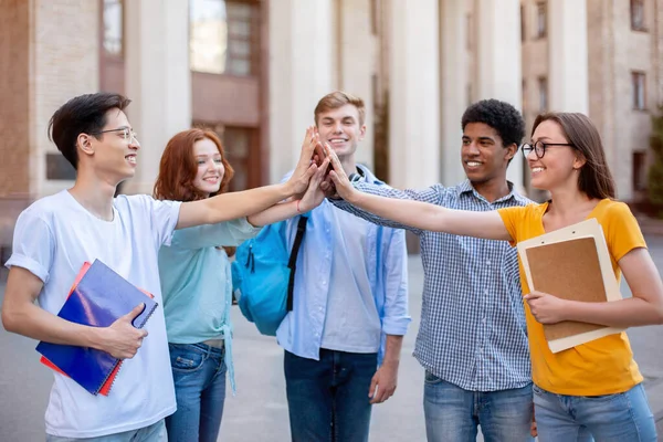 Szczęśliwi studenci dający przybicie piątce świętującej pomyślnie zdane egzaminy stojące na zewnątrz — Zdjęcie stockowe