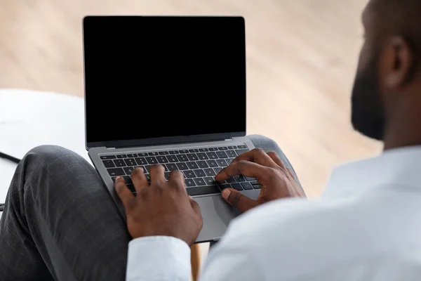 Homme afro-américain méconnaissable utilisant un ordinateur portable avec écran blanc noir, image de maquette — Photo